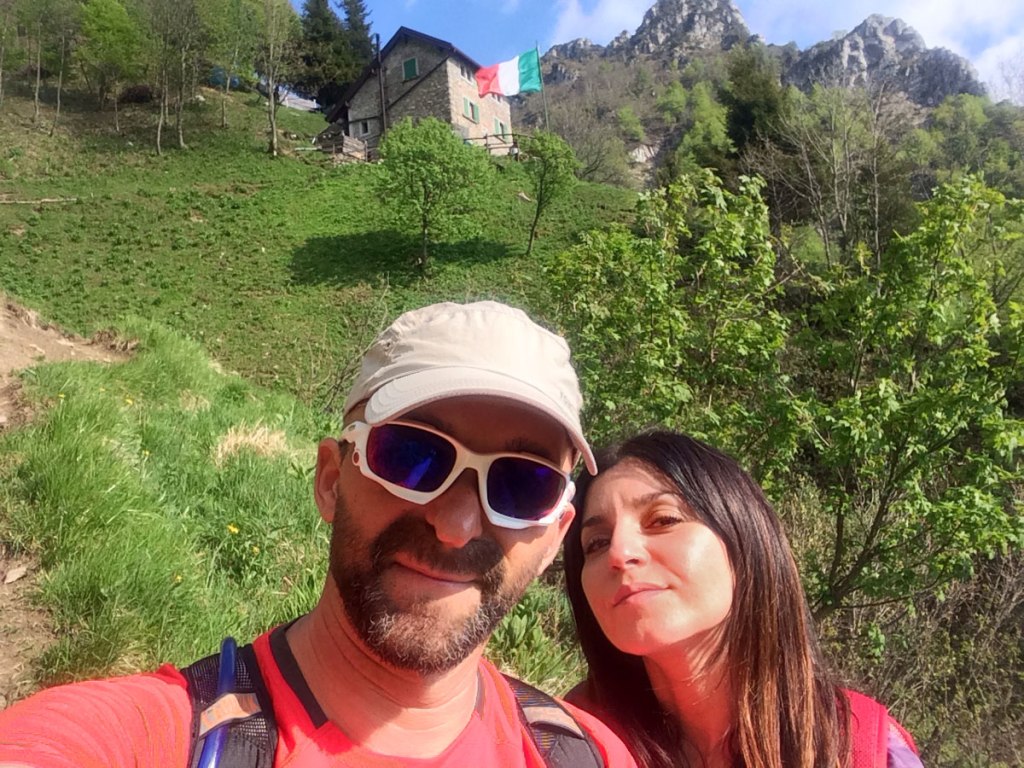 due escursionisti all’esterno del rifugio elisa con alle spalle le guglie di dolomia della Grigna Meridionale