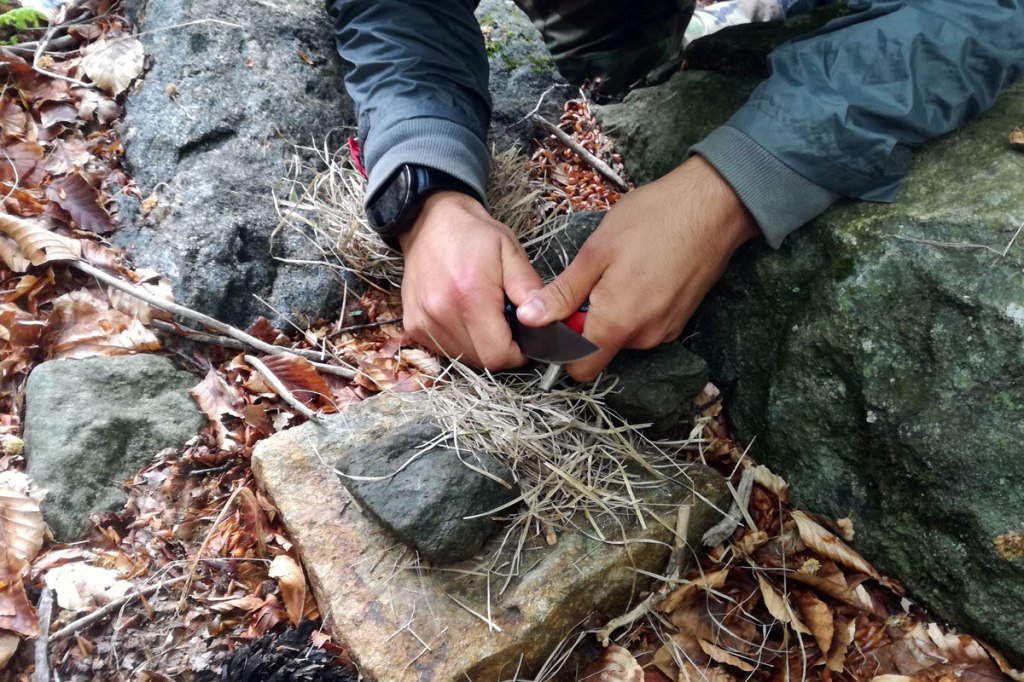 un escursionista accende il fuoco con l'acciarino