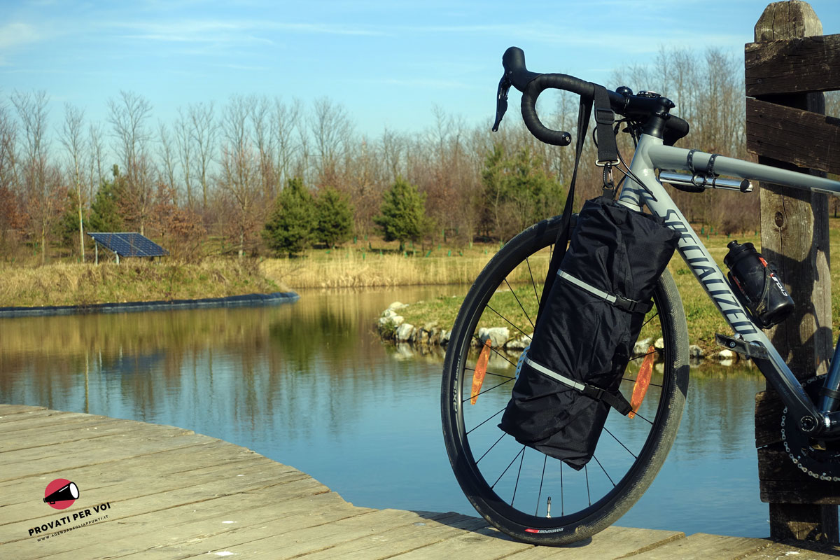 una bicicletta fotografata con una custodia porta abiti impermeabile appesa al manubrio