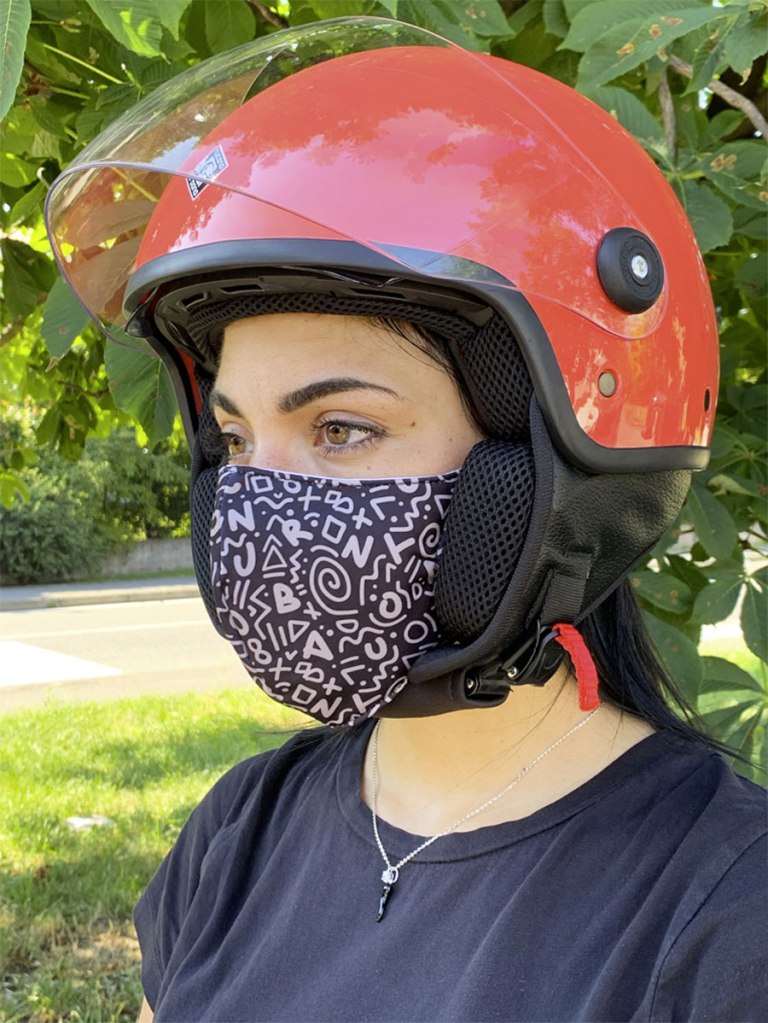 una ragazza indossa una mascherina filtrante in cotone con il casco da moto