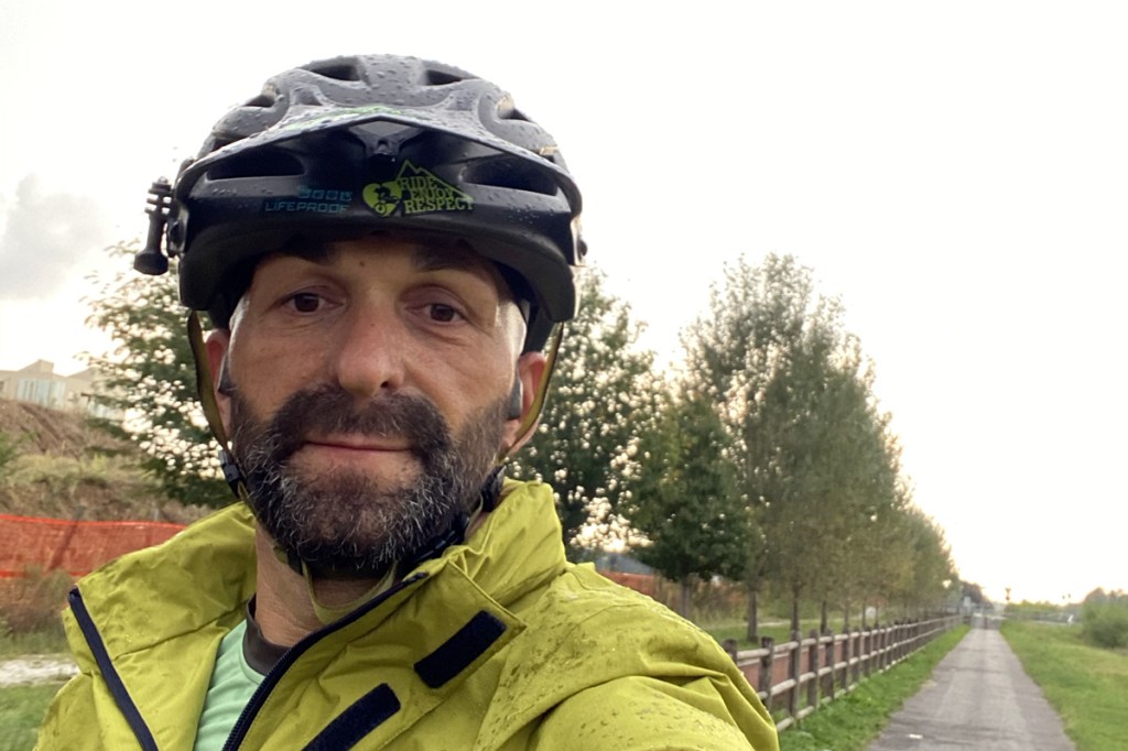 un ragazzo in bicicletta sorridente sotto la pioggia