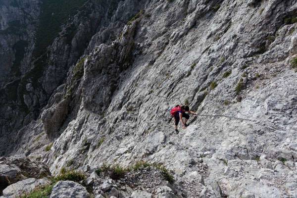 escursionista e un costone di roccia attrezzato con catene