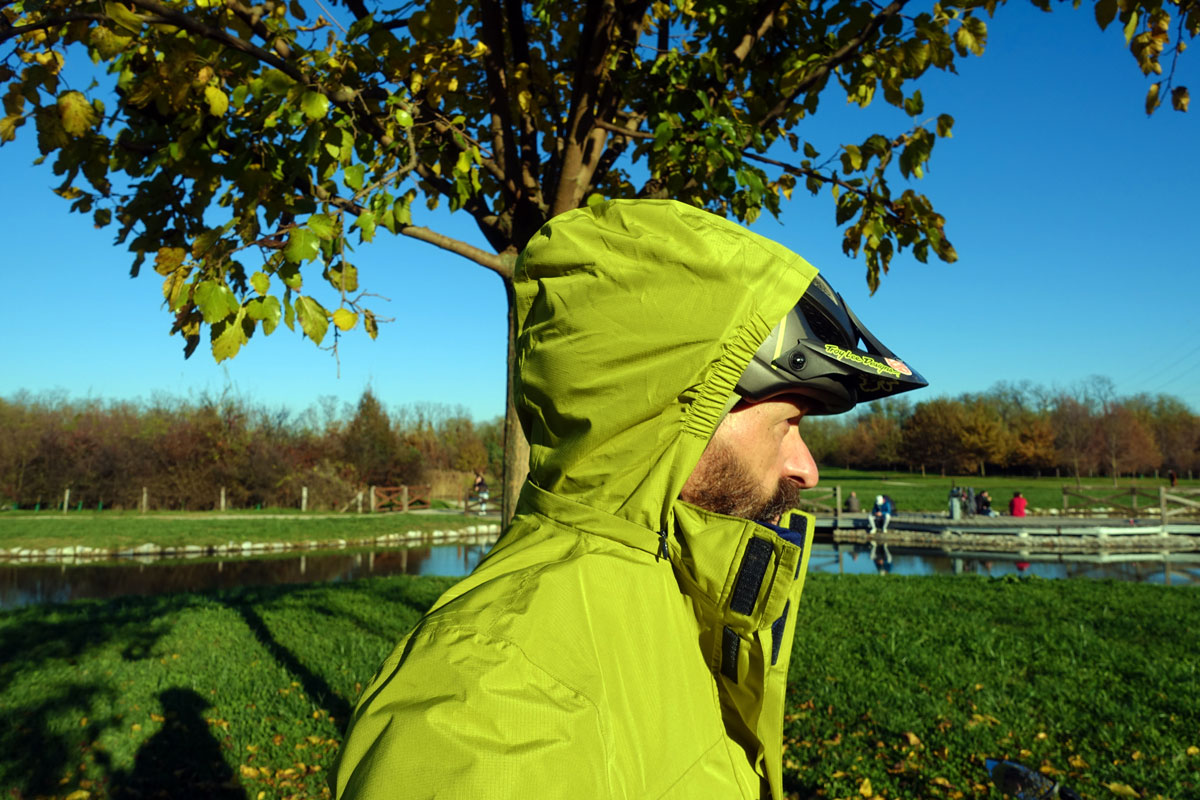 un ciclista indossa il cappuccio della giacca anti pioggia sopra il casco