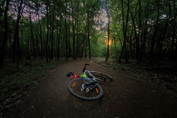 una bicicletta fotografata a terra su una strada sterrata alle luci dell'alba