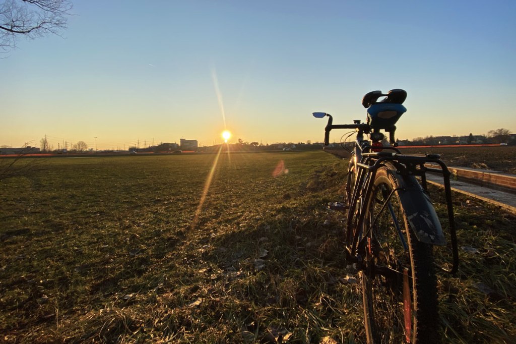 una bicicletta in primo piano fotografata con il sole al tramonto di fronte