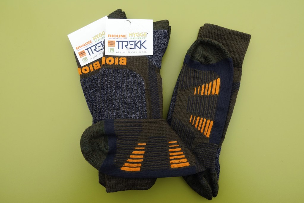 calze tecniche verde oliva con inserti arancio fotografate su sfondo verde