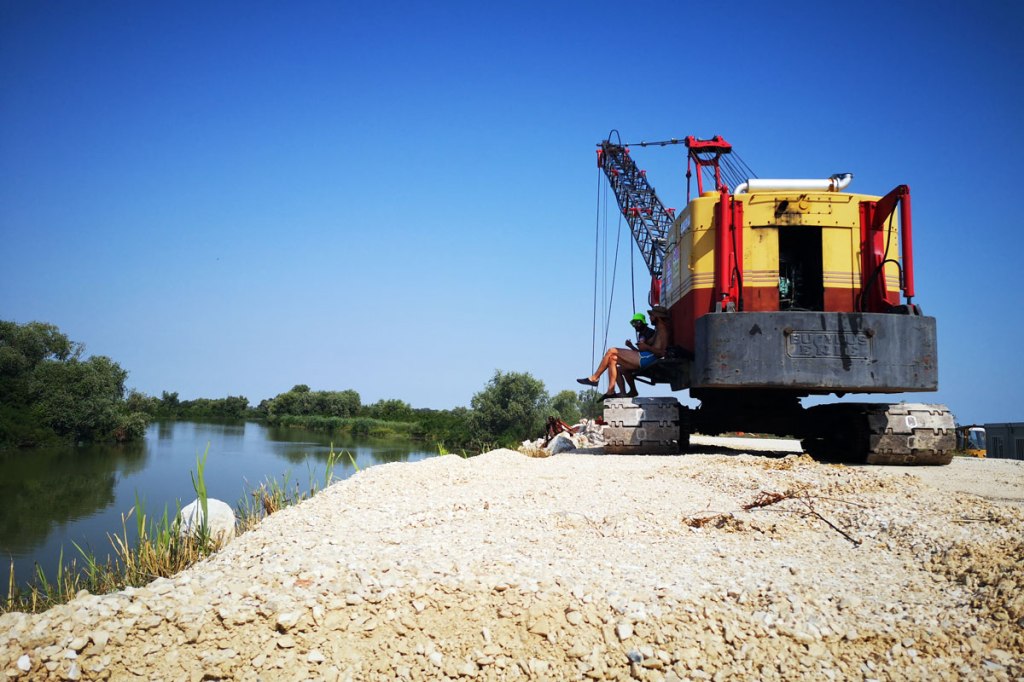 Pausa sugli argini del PO in costruzione con un escavatore in primo piano