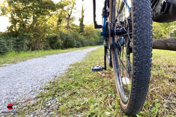 uno pneumatico in primo piano e di fianco una strada bianca con ghiaia