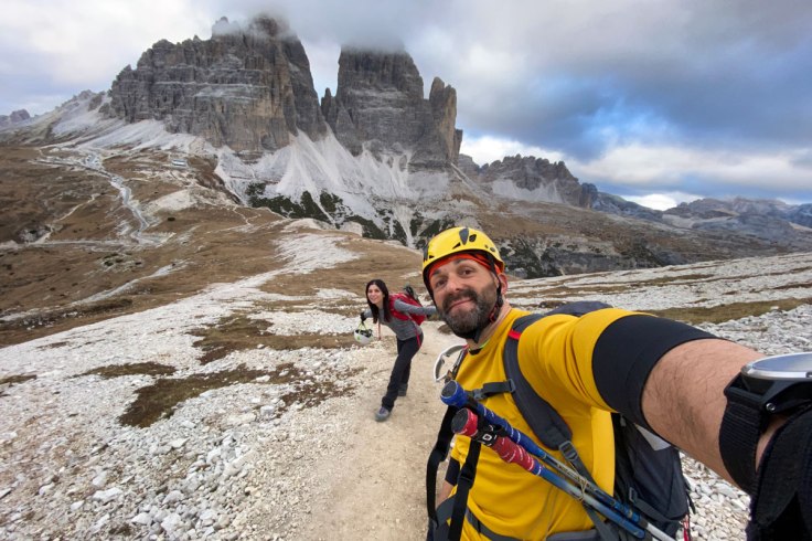 due escursionisti si scattano un selfie con le tre cime di lavaredo alle spalle