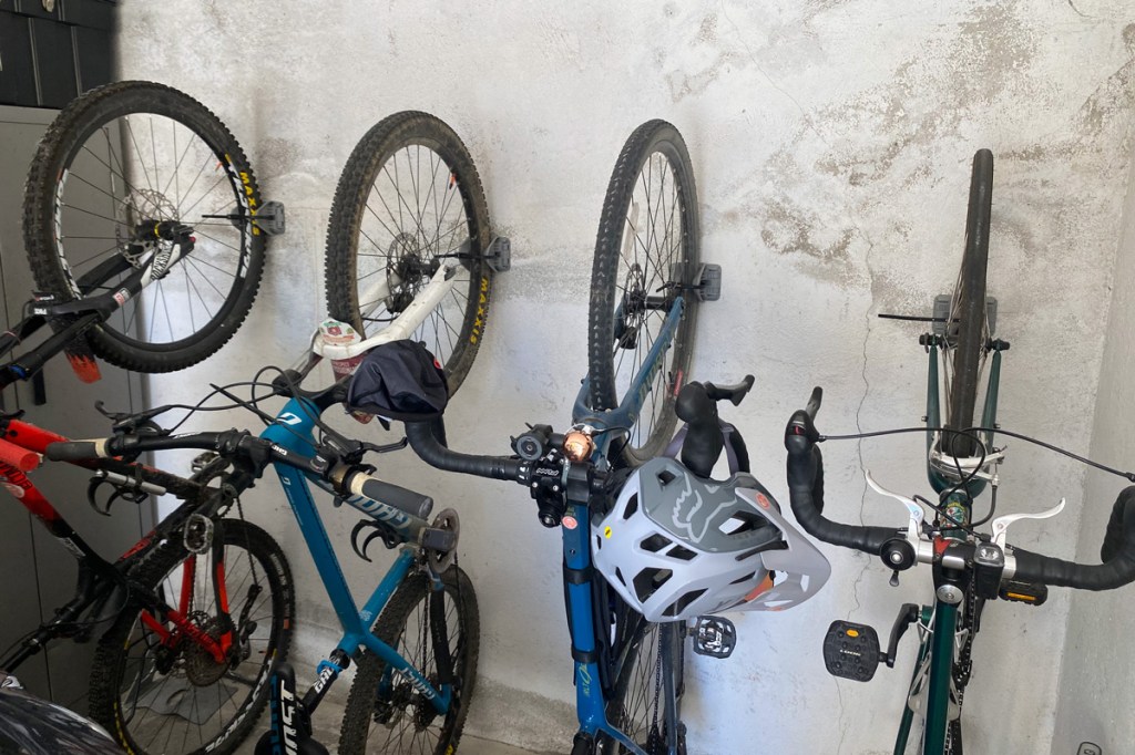 4 biciclette all'interno di un box sono sistemate verticalmente ed in ordine grazie all'utilizzo di un nuovo sistema di fissaggio a muro verticale