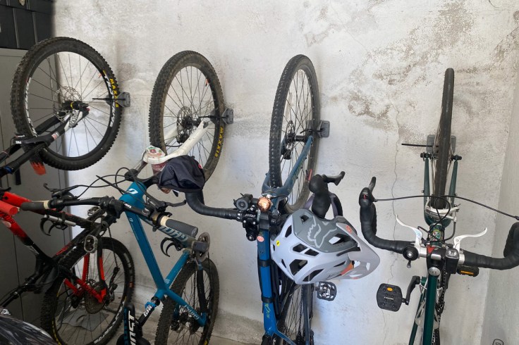 4 biciclette all'interno di un box sono sistemate verticalmente ed in ordine grazie all'utilizzo di un nuovo sistema di fissaggio a muro verticale