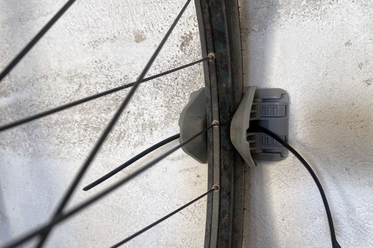 un supporto da muro in plastica grigia per bicicletta la mantiene in verticale attraverso la ruota anteriore agganciata