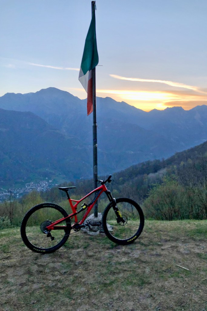 una mountain bike vicino alla bandiera dell'Italia sulla vetta di una montagna