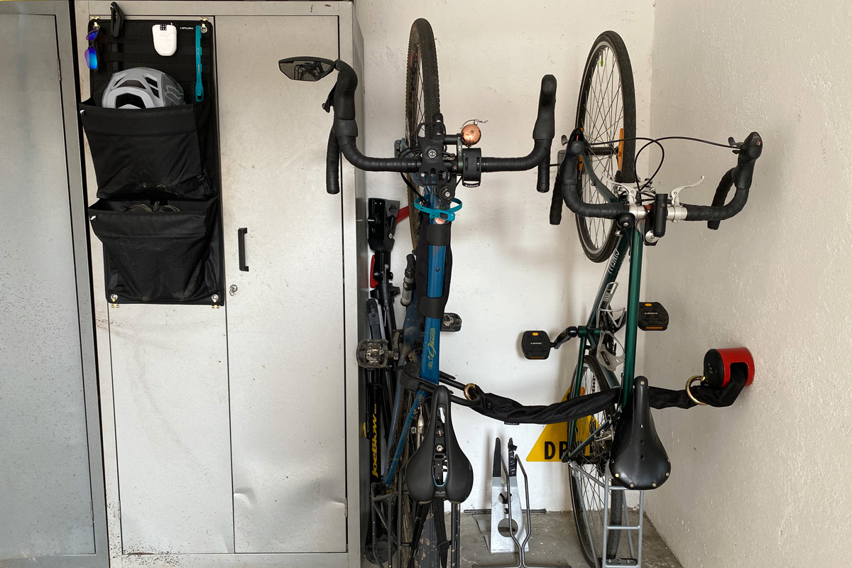due biciclette sistemate in verticale grazie ad un supporto per la ruota anteriore e un portaoggetti che contiene casco, scarpe e altro