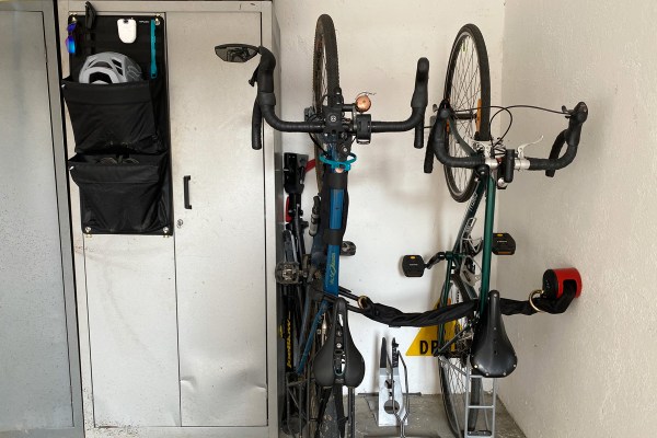 due biciclette sistemate in verticale grazie ad un supporto per la ruota anteriore e un portaoggetti che contiene casco, scarpe e altro