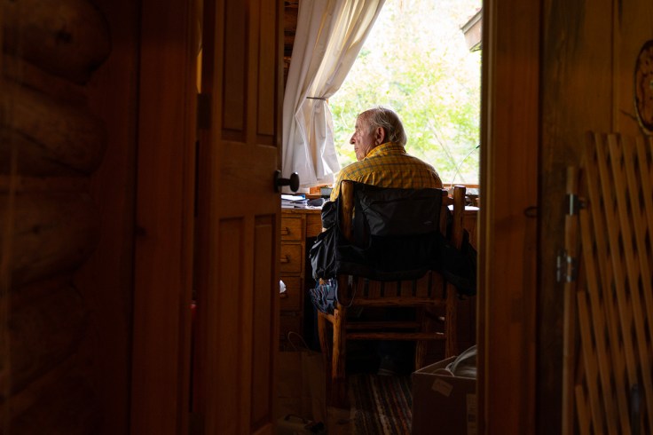 un anziano signore all'interno del suo studio in una casa di montagna in legno