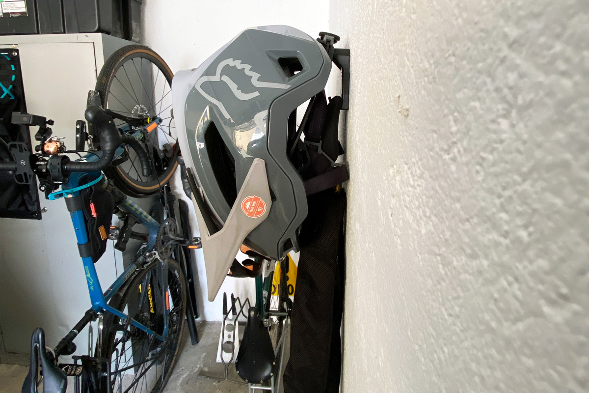 primo piano su un casco per bici appeso al supporto a muro di un lucchetto a catena per bici