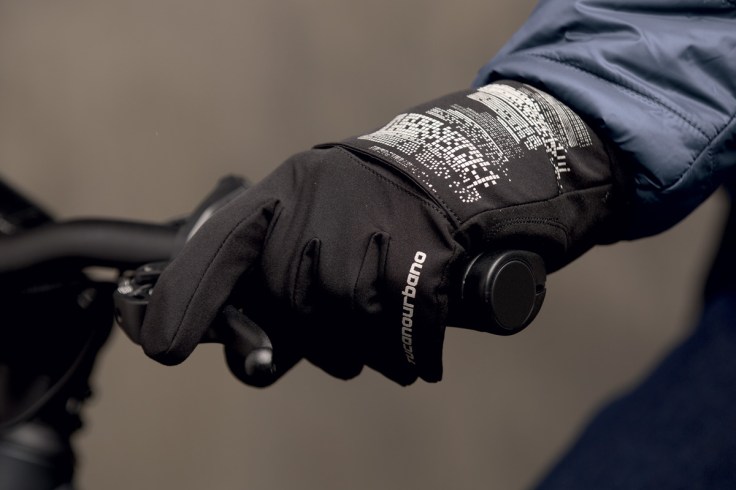 una mano che calza un guanto invernale impugna il manubrio di una bicicletta mentre il dito indice è ben saldo sul freno