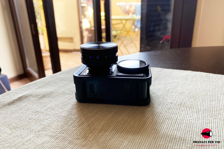 un diffusore audio a conduzione superficiale di colore nero è appoggiato su una action camera di colore nero