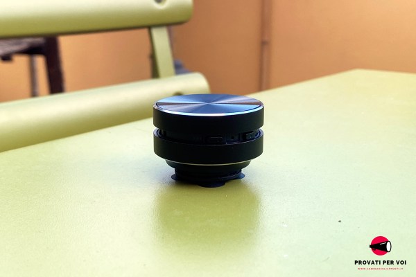 un diffusore audio a conduzione superficiale di colore nero è appoggiato su un tavolo d'acciaio di colore verde pistacchio