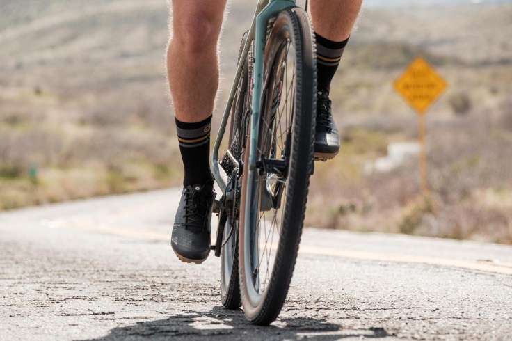 un ciclista crossista in azione su una strada asfaltata in sella alla sua bicicletta gravel bike per le avventure e l'esplorazione fuoristrada