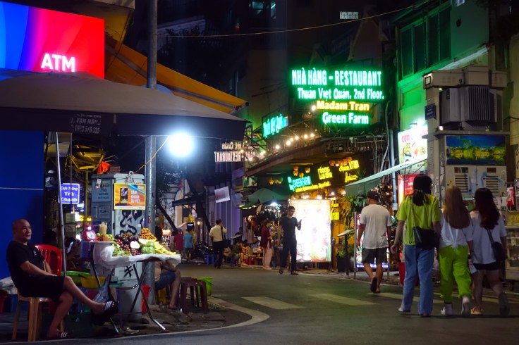 una via di Hanoi, capitale del Vietnam, affollata di insegne luminose che si sovrappongono una all'altra