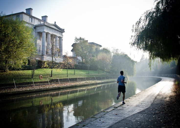 un edificio monumentale sulla riva di un canale e un podista impegnato a correre