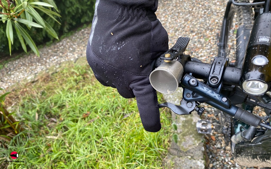 Il dito indice di una mano che calza un guanto invernale mostra la presa con il dito sulla leva freno della bicicletta