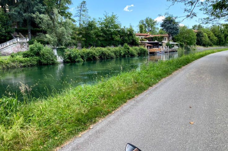 Pista ciclabile lungo un canale immerso nel verde nella campagna lombarda percorsa in bicicletta.