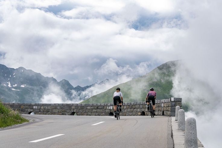 Ciclisti affrontano una salita alpina immersi nelle nuvole