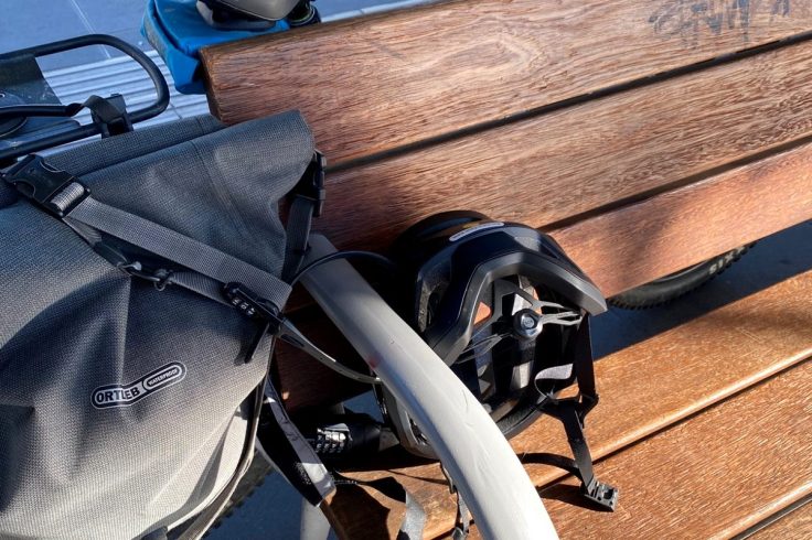 Casco e borsa fissati con Hiplok Z LOK COMBO presso una stazione ferroviaria