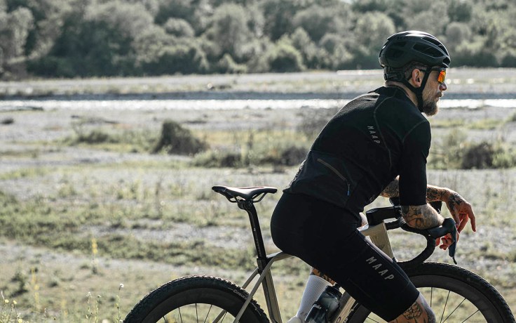 un ciclista appassionato di gravel bike in sosta lungo un percorso sterrato in riva al fiume
